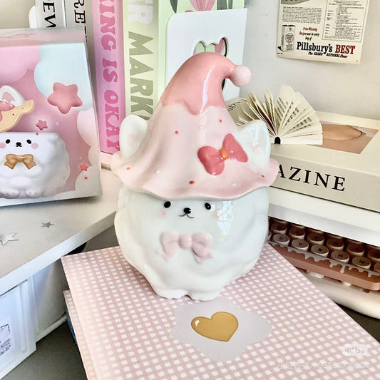 Cute plush Samoyed with a pink hat on a checkered surface with books and stationery items in the background.