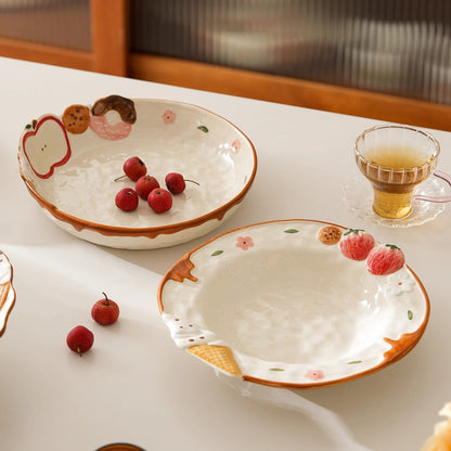 Two ceramic bowls with fruit designs on a table with a glass of tea.