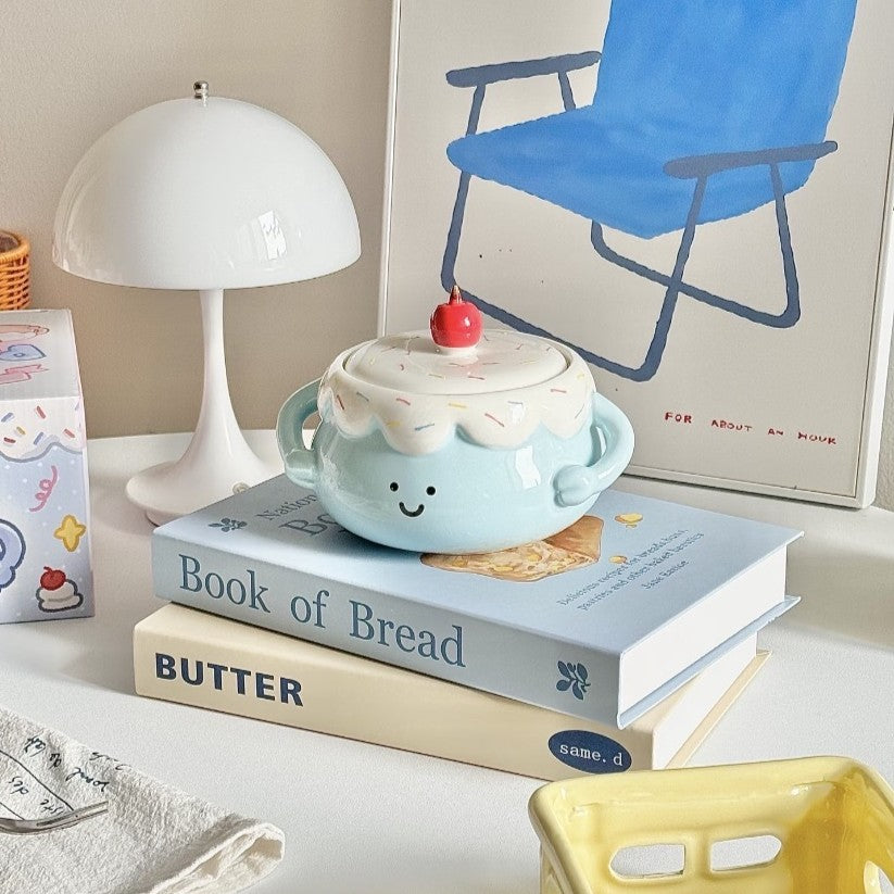 Ceramic cup with lid and cherry on top on books with a lamp and chair in the background