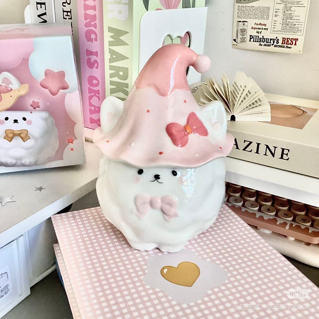 Cute plush Samoyed with a pink hat on a checkered surface with books and stationery items in the background.