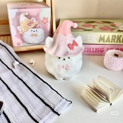 Cute ceramic Samoyed with a pink hat on a surface with stationery items.
